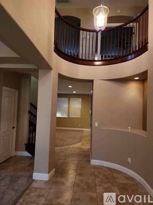 A living room with a balcony and a chandelier.