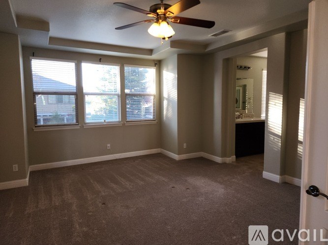 A room with a ceiling fan and carpeted floor.