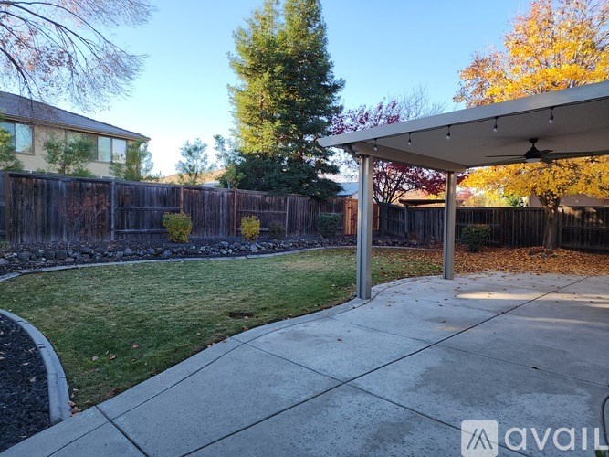 A backyard with a patio and a fence.
