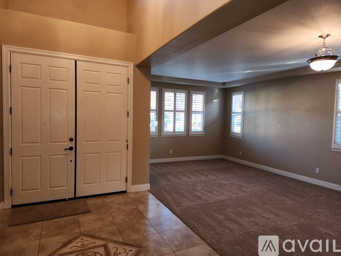 A room with a carpeted floor and a rug, two doors, and a window.