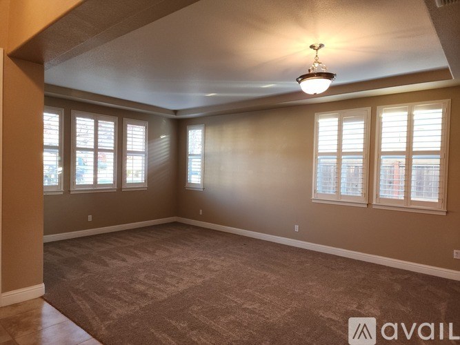 A room with carpeted floor, a ceiling light, and a window with blinds.