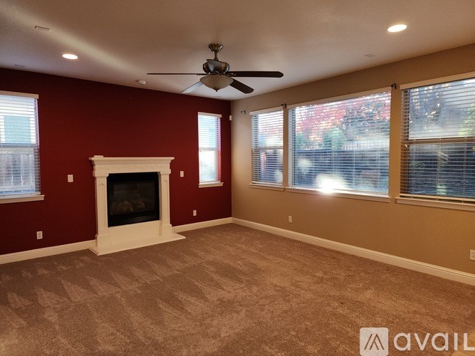 A living room with a fireplace and a ceiling fan.