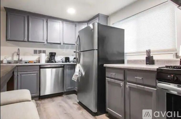 A kitchen with a black refrigerator and stainless steel appliances.
