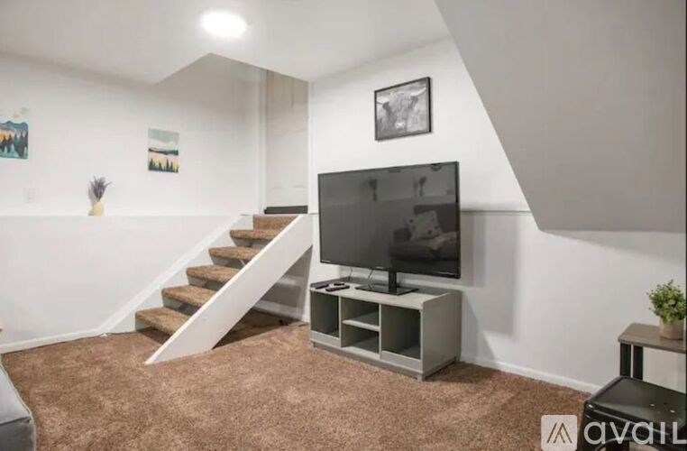 A living room with a television and stairs.