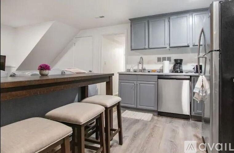A kitchen with a refrigerator, stove, and bar stools.