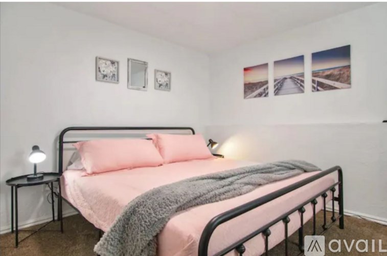 A bedroom with a bed, a small table, and pictures on the wall.