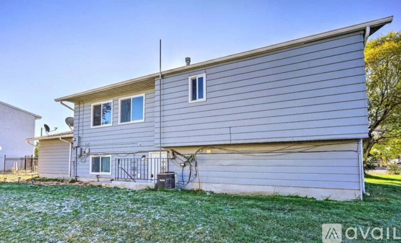 A house with a grey siding and a white window is for sale.