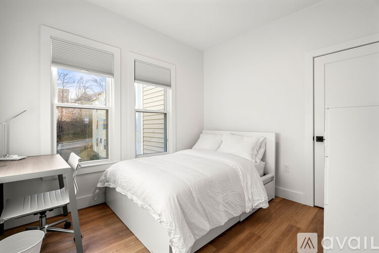 A white bedroom with a bed, desk, and chair.