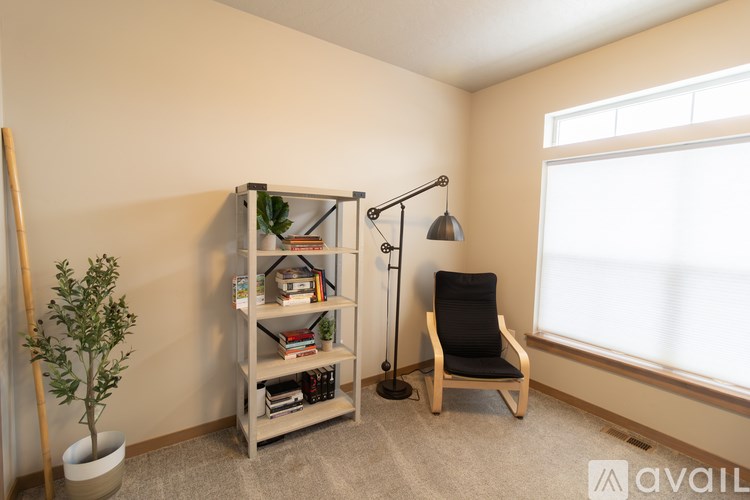 A room with a chair, a plant, a bookshelf, and a lamp.