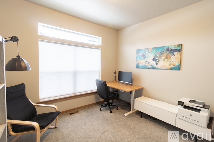 A room with a desk, chair, and a painting on the wall.