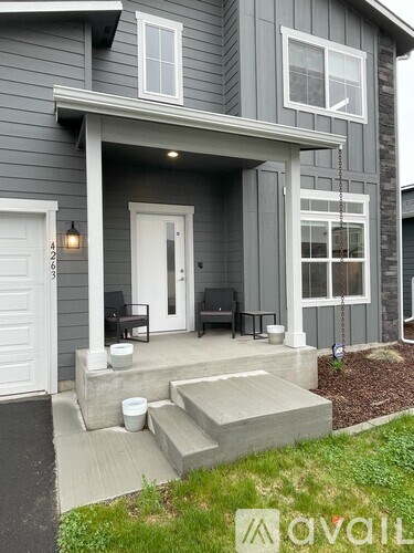 A grey house with a white door and a small porch.