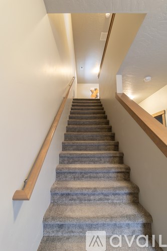 A staircase with a wooden handrail and a carpeted runner.