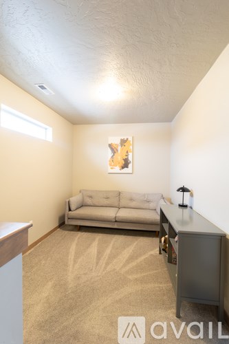 A living room with a couch, a table, and a painting on the wall.
