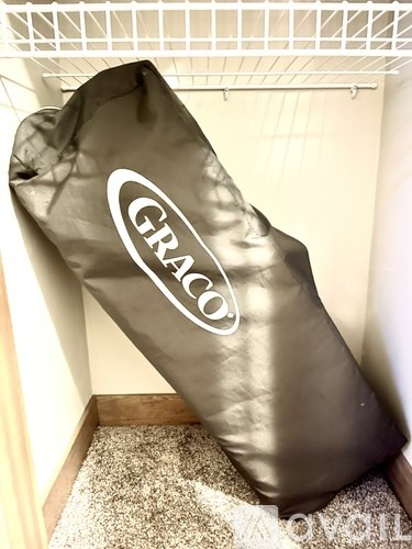 A Graco branded item is sitting on a carpeted floor.