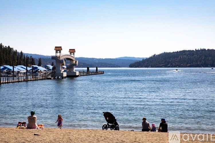 A family is enjoying a day at the beach near a dock with a small building on it.
