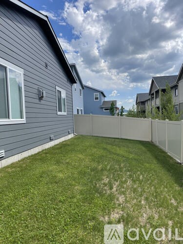 A backyard with a fence and a house in the background.