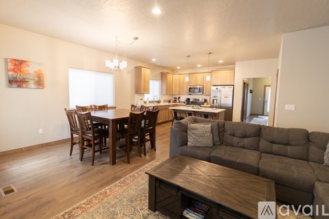 A living room with a brown couch and a dining table with chairs.