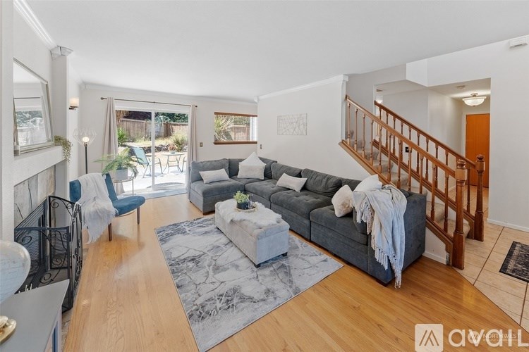 A living room with a grey couch and a wooden staircase.