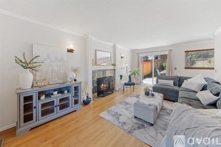 A living room with a grey sofa, a grey coffee table, a grey cabinet, a fireplace, and a painting on the wall.