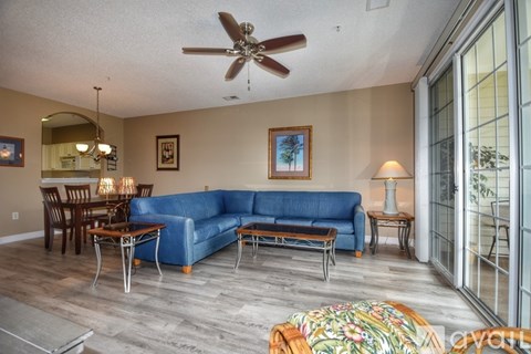 A living room with a blue couch and a ceiling fan.