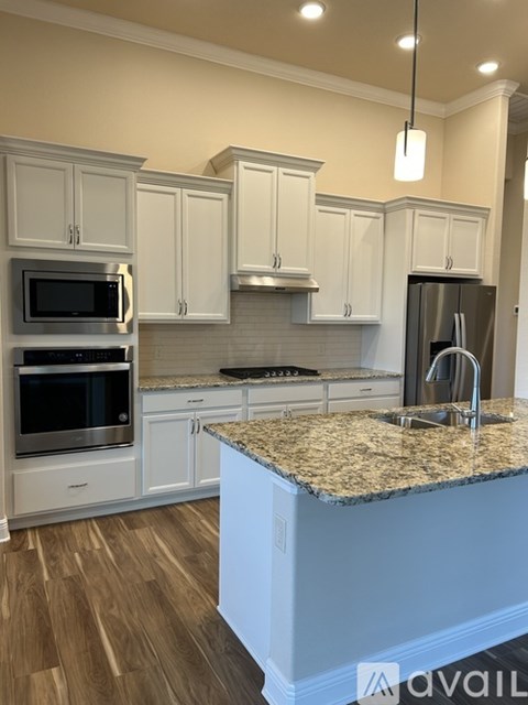 A kitchen with a granite countertop and stainless steel appliances.