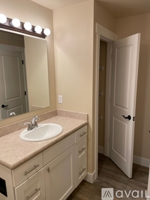 A bathroom with a sink, mirror, and lighting fixture.