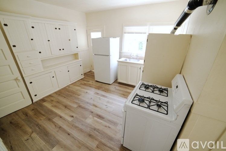 A kitchen with a white gas stove and wooden floors.
