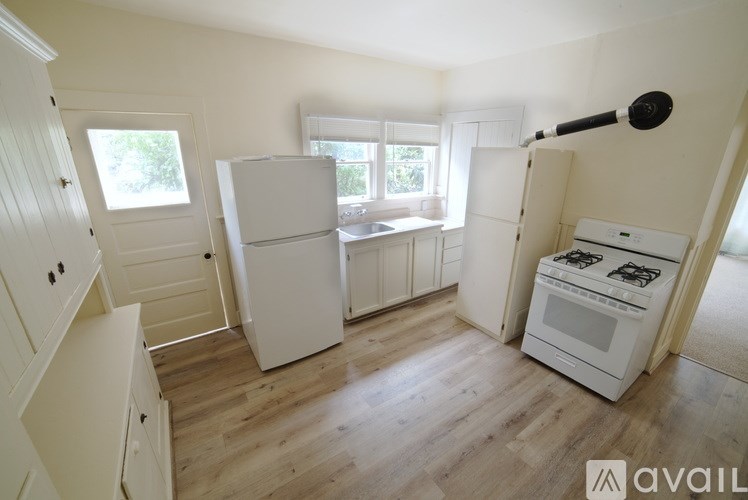 A kitchen with white appliances and wooden floors.