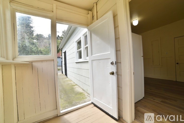A white door is open to a room with wooden floors and walls.
