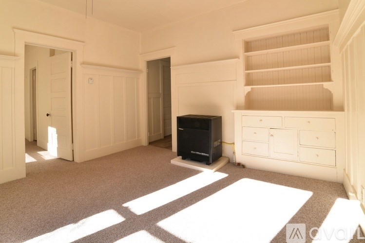 A black television set sits on a white rug in a room with white walls and a white ceiling.