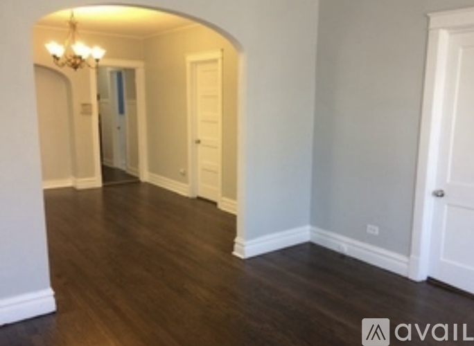 A hallway with a chandelier and wood floors.