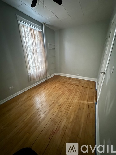 A room with wooden flooring and a window with curtains.