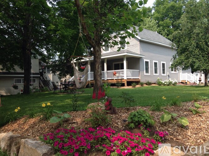 A house with a porch and a hammock in the front yard.