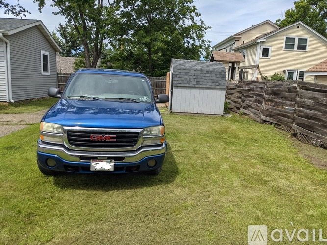 A blue GMC truck is parked in a grassy yard.