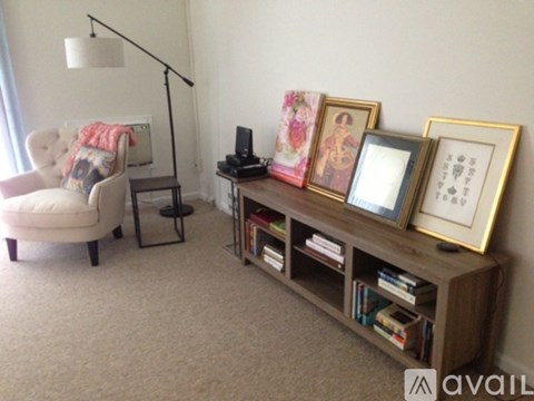 A living room with a chair, a table, and a bookshelf with books and picture frames.