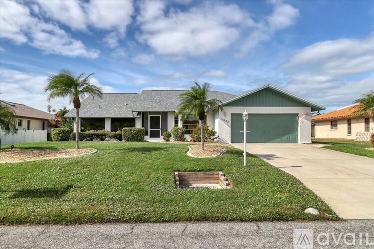 A house with a green lawn and a palm tree in front.