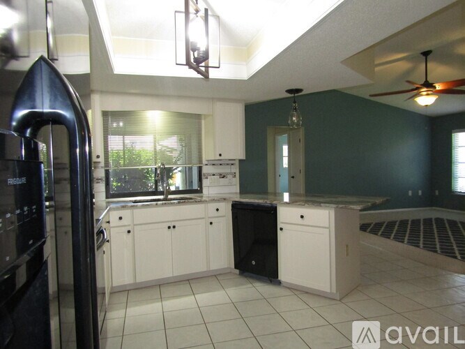 A kitchen with white cabinets and a black refrigerator.
