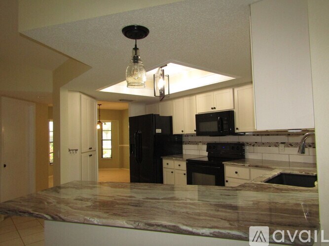 A kitchen with black appliances and a marble countertop.