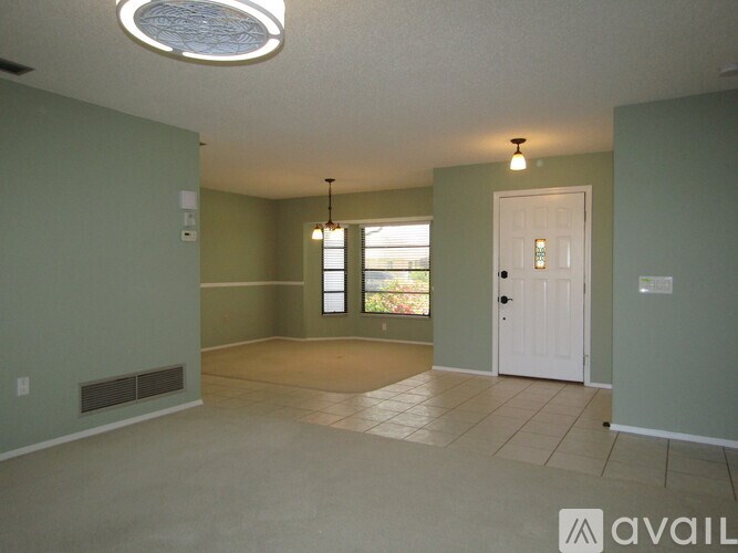 A room with a white door and a window with a view of trees.