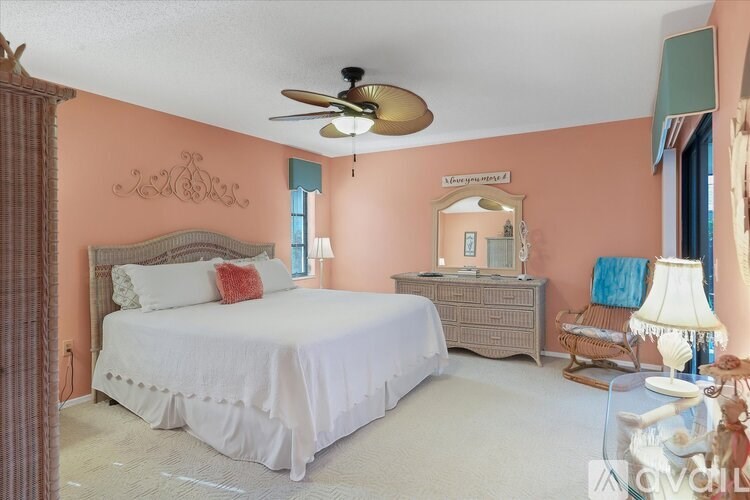 A bedroom with a bed, dresser, and ceiling fan.