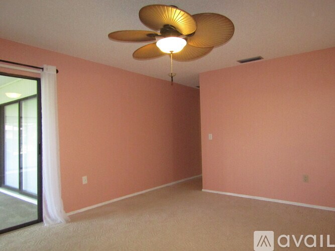 A room with a ceiling fan and a sliding glass door.