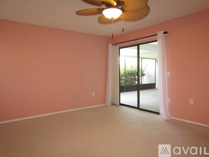 A room with a ceiling fan and sliding glass doors.