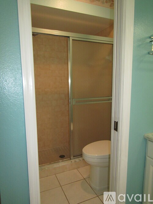 A white toilet sits in a bathroom with a glass shower door.