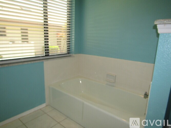 A white bathtub in a bathroom with a window.