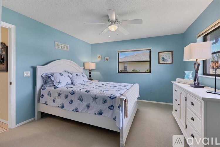A bedroom with a bed, dresser, and ceiling fan.