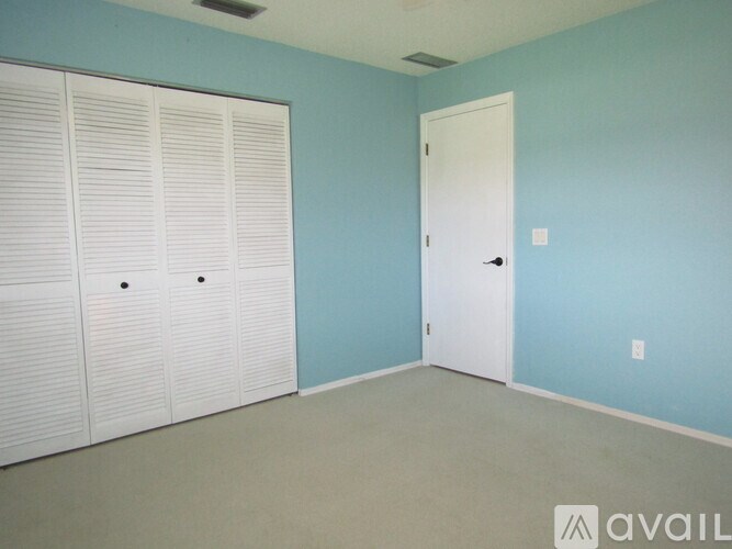 A room with a white door and a wall of white closet doors.