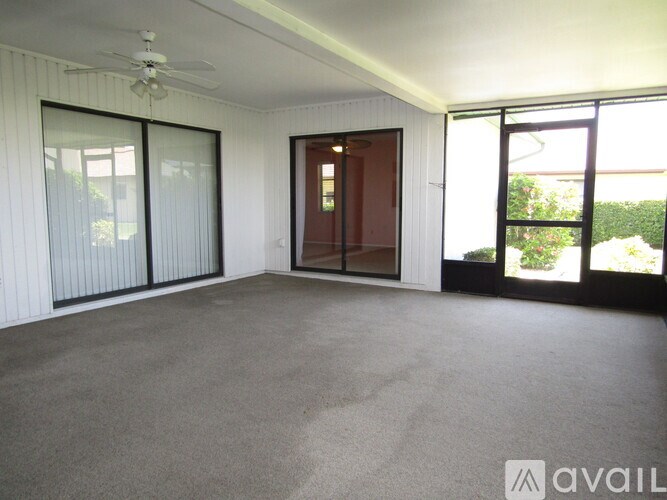 A room with a ceiling fan and sliding glass doors.