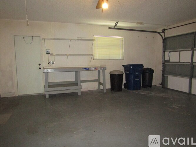 A room with a white door, a window with blinds, a table, and two bins.