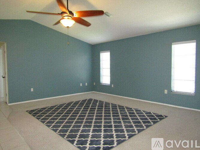 A room with a ceiling fan and a rug on the floor.
