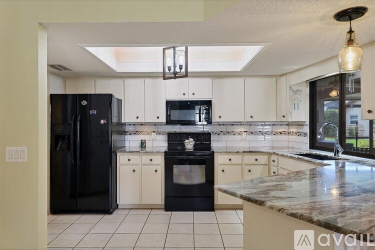 A kitchen with black appliances and white cabinets.